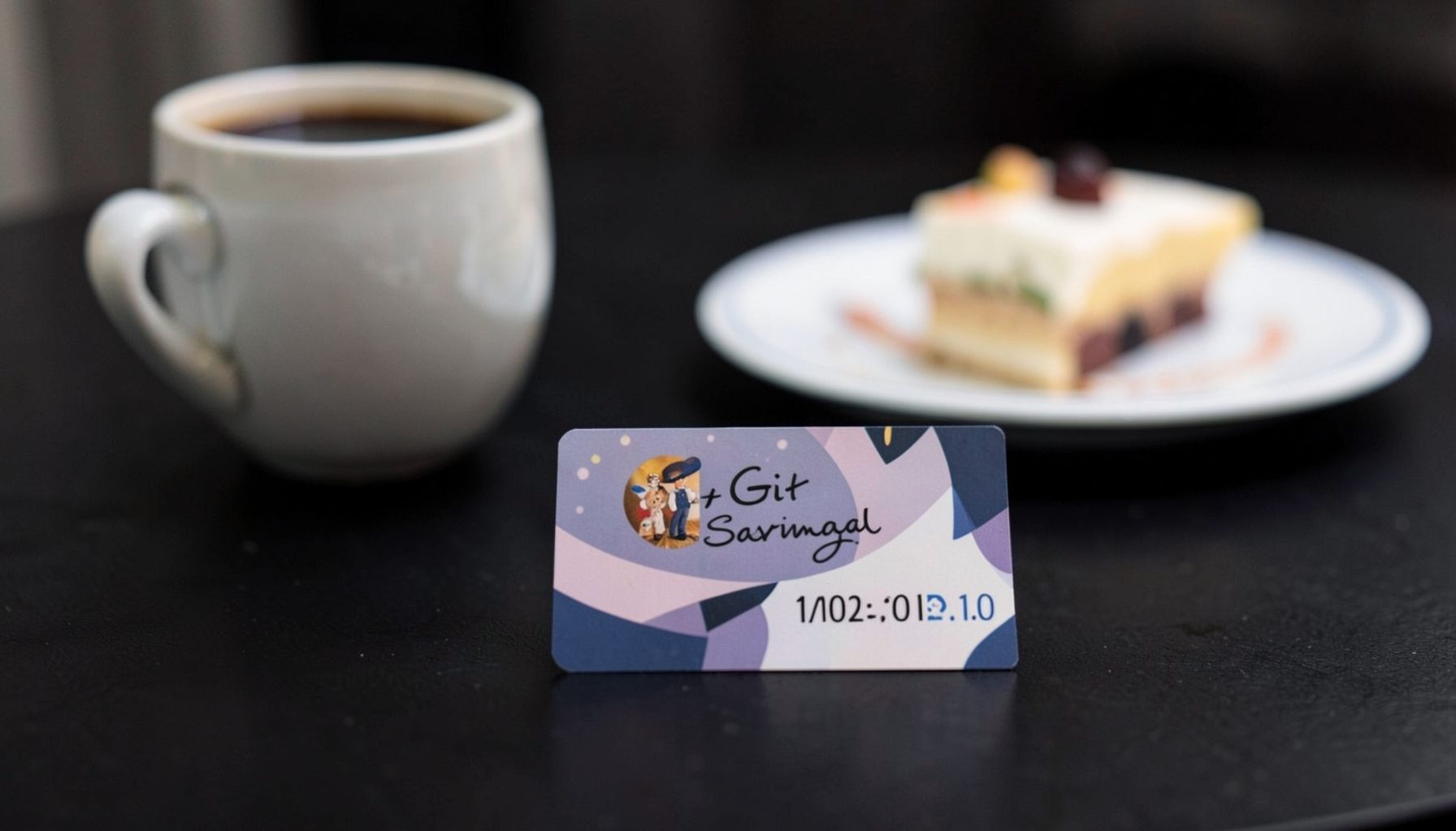 Gift card displayed on a dark tabletop with a coffee cup and dessert plate in soft focus behind